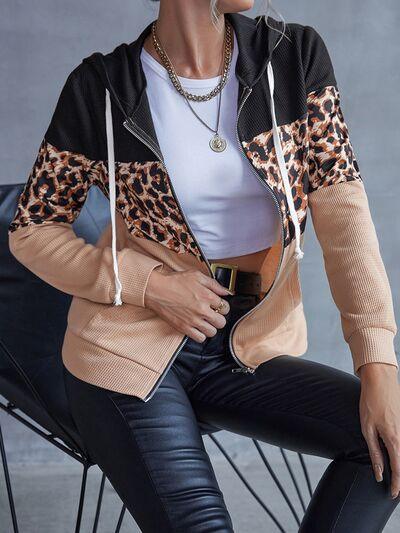 a woman sitting on a chair wearing a leopard print jacket