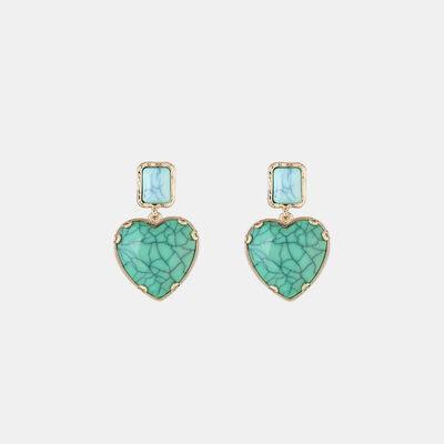 a pair of earrings with a heart shaped stone