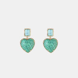 a pair of earrings with a heart shaped stone