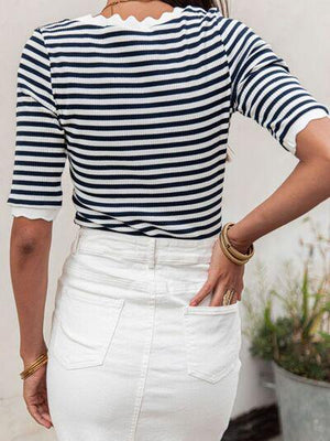 a woman wearing a striped top and white skirt