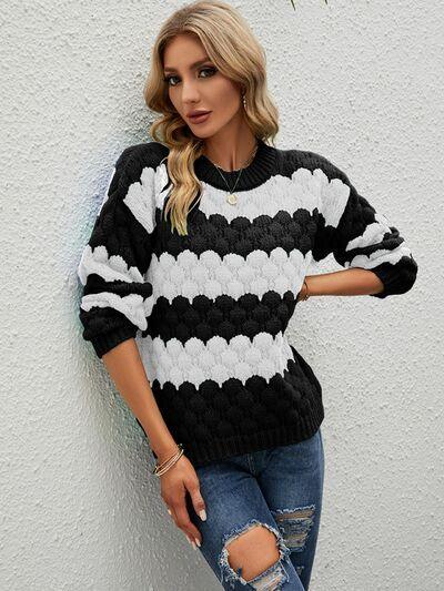 a woman leaning against a wall wearing a black and white sweater