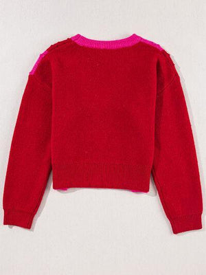 a red sweater hanging on a white wall