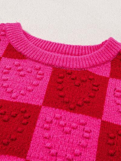 a pink and red sweater sitting on top of a white table