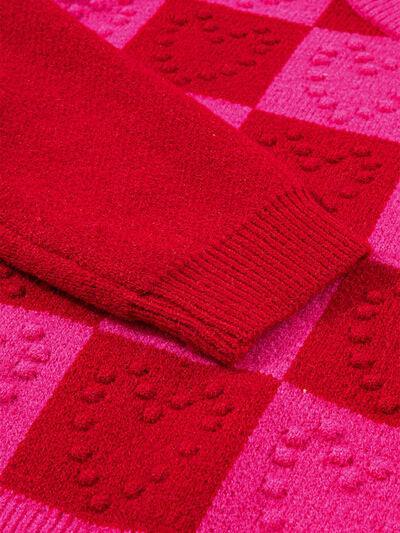 a red sweater laying on top of a pink blanket