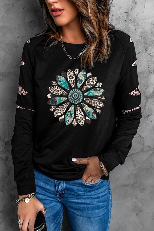 a woman wearing a black sweater with a flower design