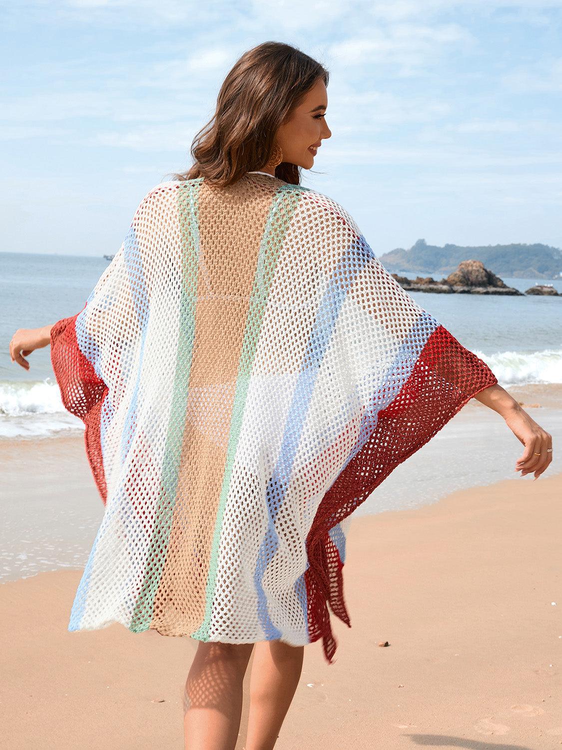 a woman is walking on the beach with a colorful blanket