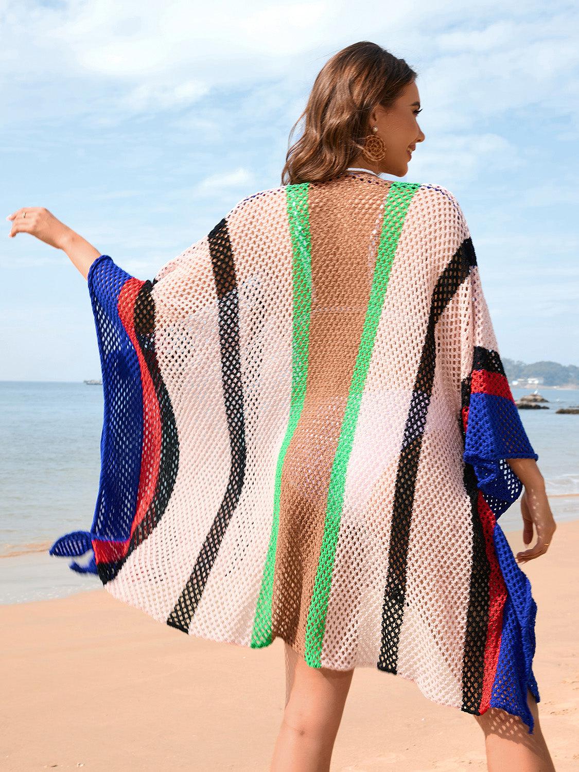 a woman walking on a beach with a colorful cover up