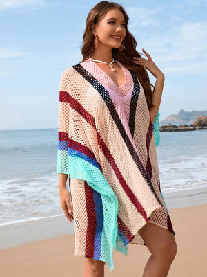 a woman standing on a beach wearing a colorful ponchy