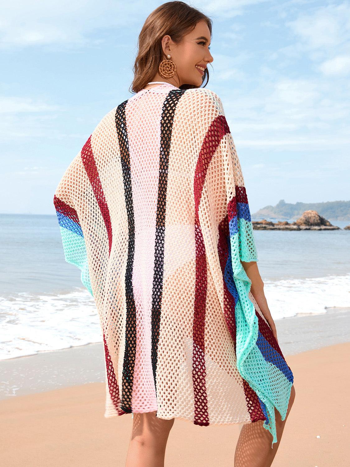 a woman standing on a beach holding a towel