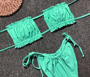 two pieces of green swimsuit sitting on top of a carpet