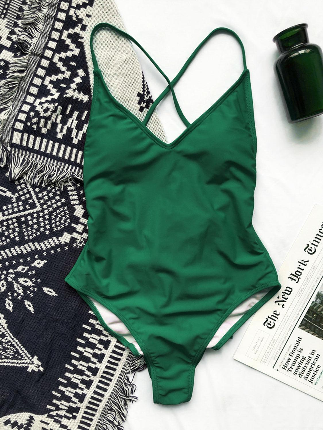 a green swimsuit sitting on top of a bed next to a magazine