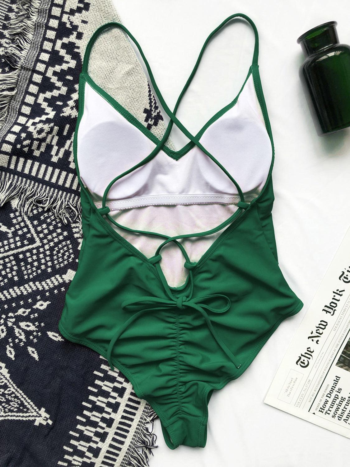 a woman's green and white swimsuit laying on top of a bed