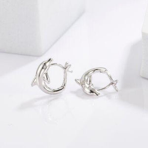 a pair of silver earrings on a white surface