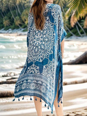 a woman standing on a beach wearing a blue and white cover up