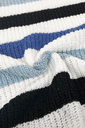 a black, white, and blue striped blanket laying on top of a bed