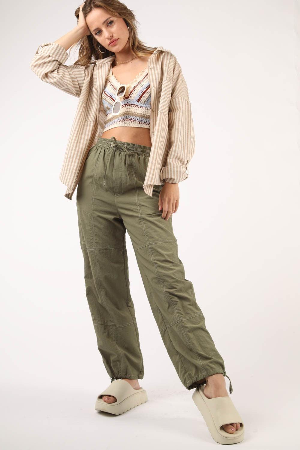 a woman is posing for a picture wearing green pants