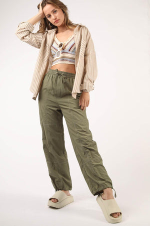 a woman is posing for a picture wearing green pants