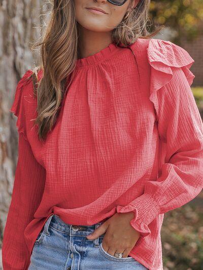 a woman wearing a red blouse and jeans