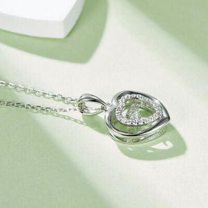a diamond pendant on a chain on a table