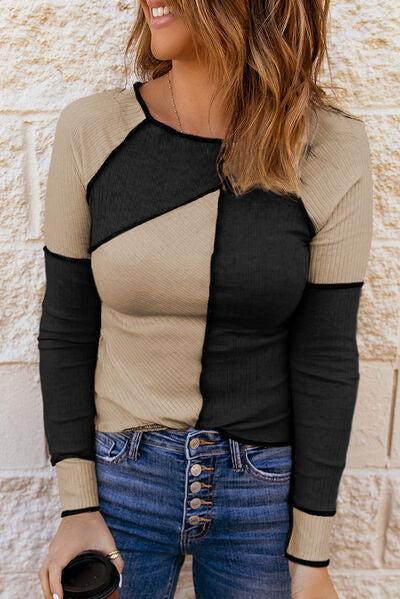 a woman wearing a black and tan top and jeans