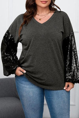 a woman wearing a black top with sequin sleeves