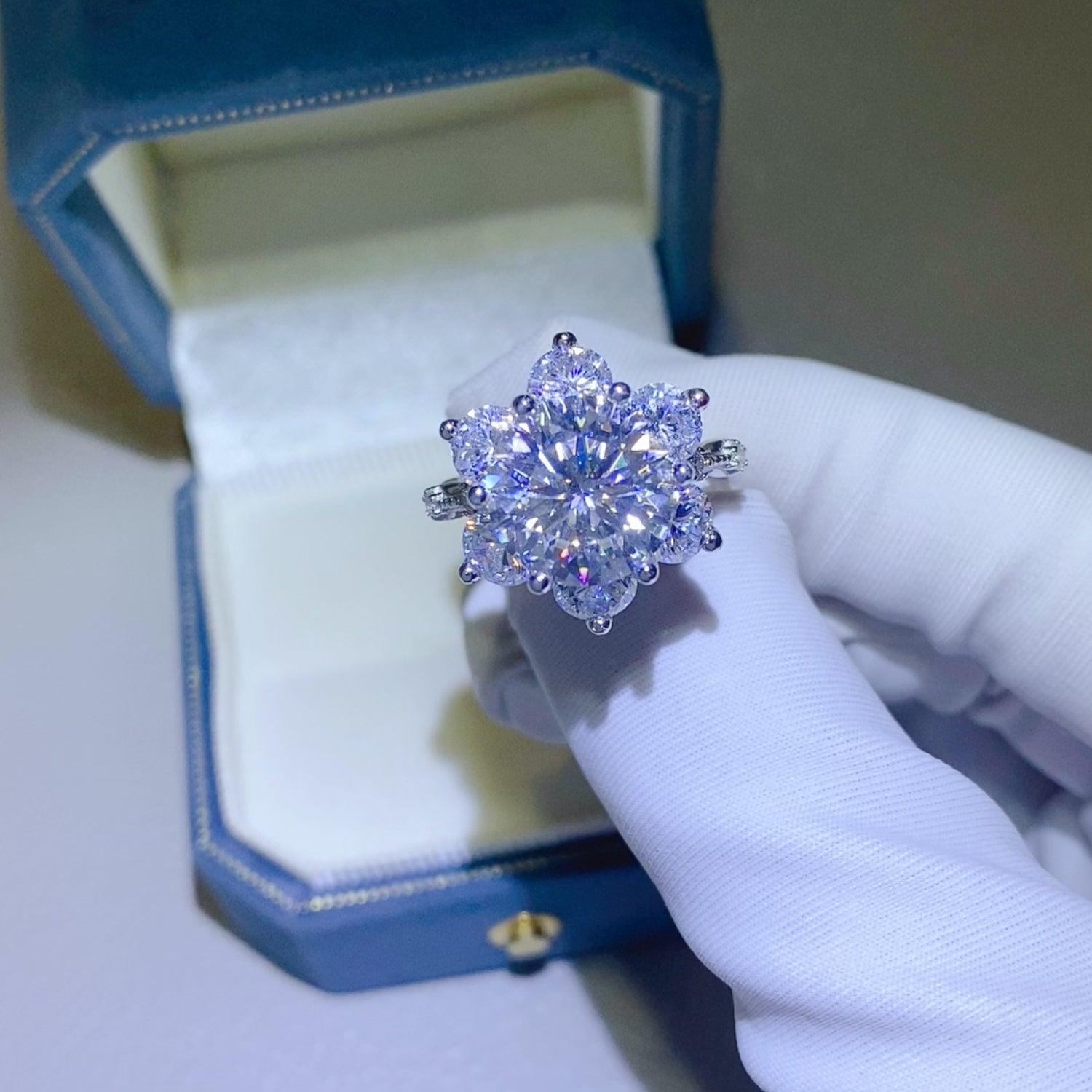 a woman's hand holding a diamond ring in a blue box