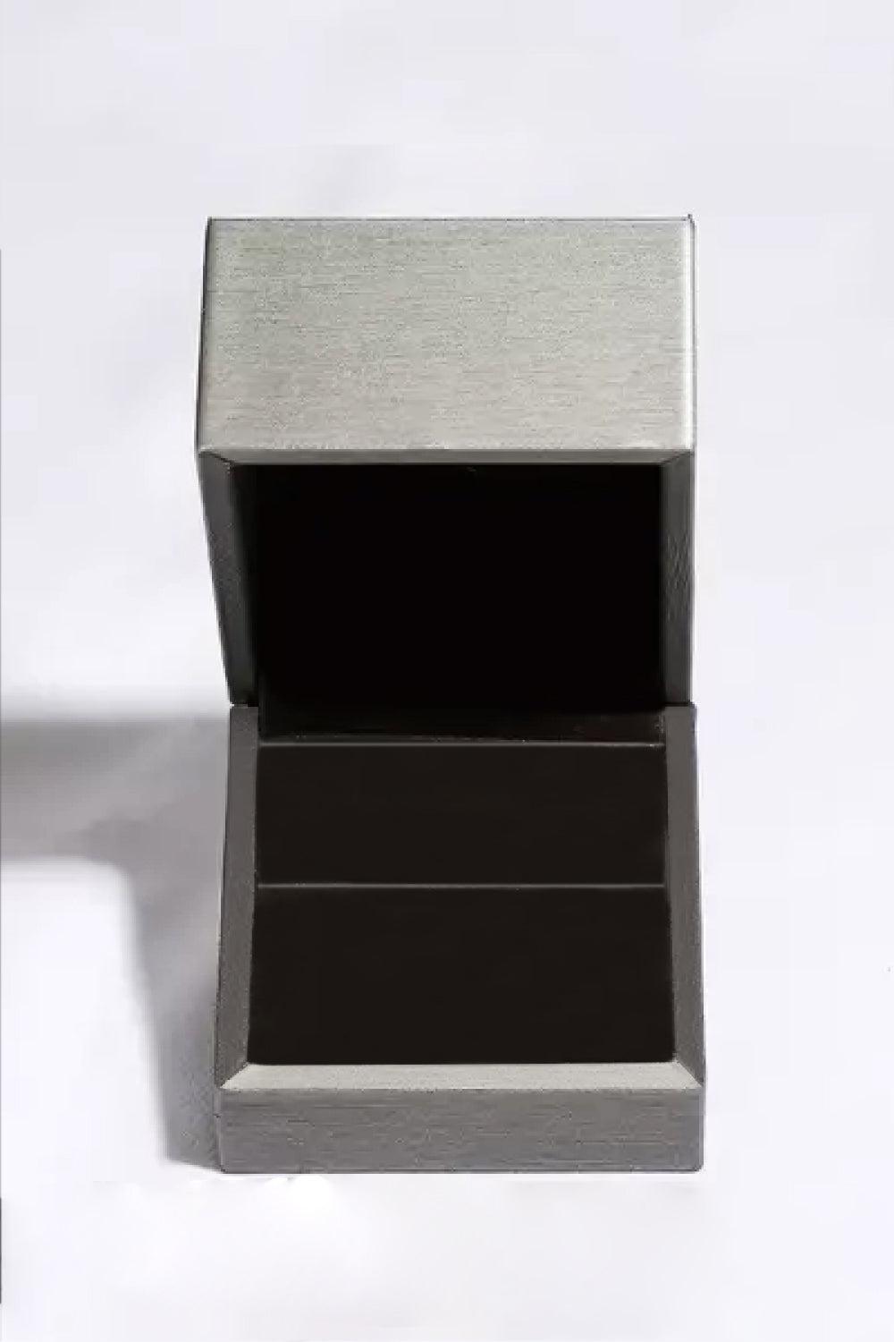 a silver ring with a black box on a white surface