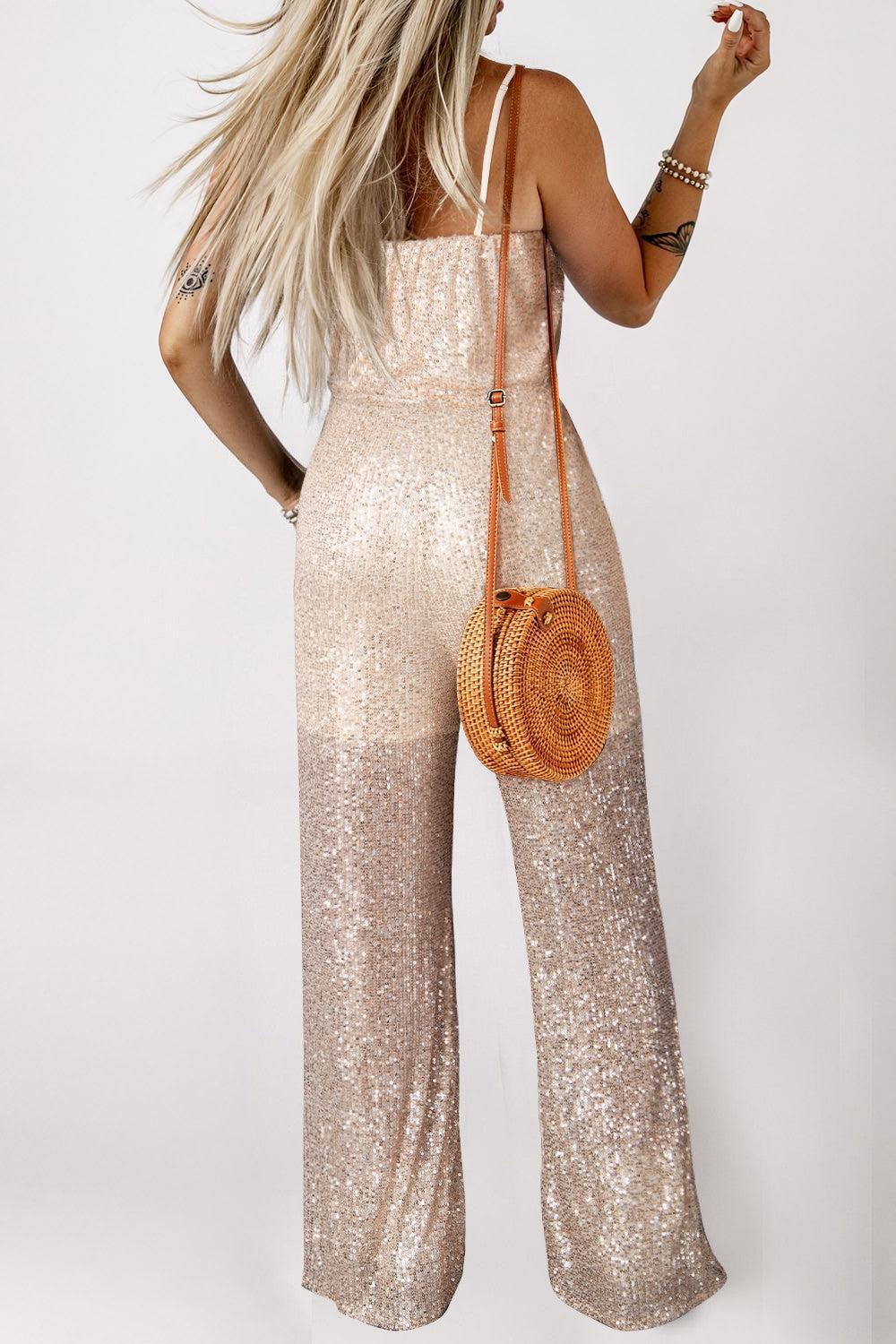 a woman in a gold sequin jumpsuit holding a straw bag