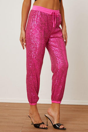 a woman wearing pink sequin pants and heels