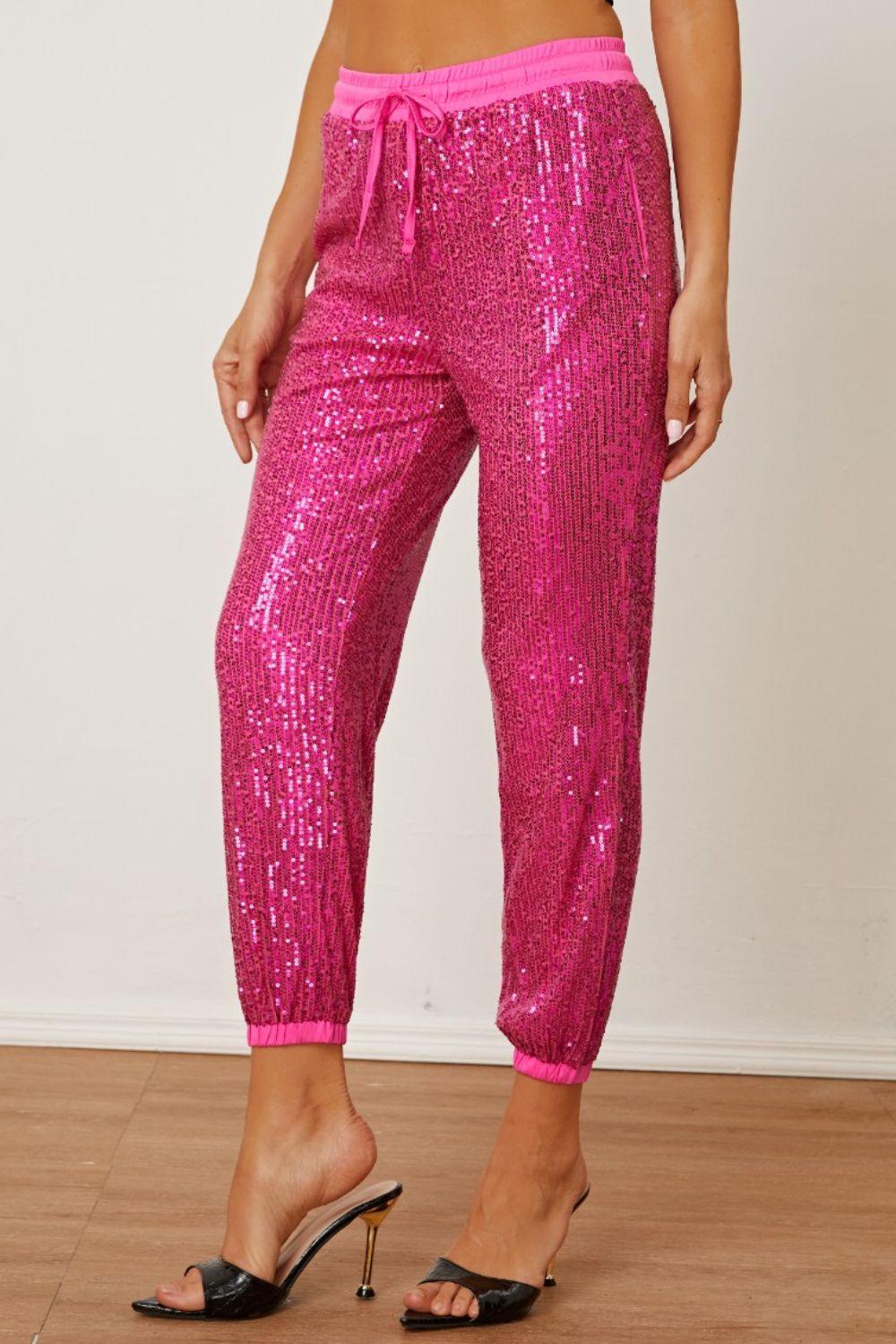 a woman wearing pink sequin pants and heels