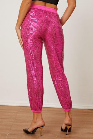 a woman in a black top and pink sequin pants