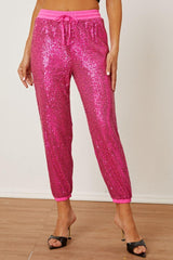 a woman wearing pink sequin pants and a crop top