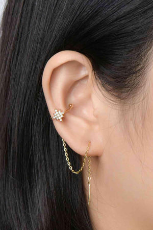 a woman wearing a gold chain ear cuff with a flower