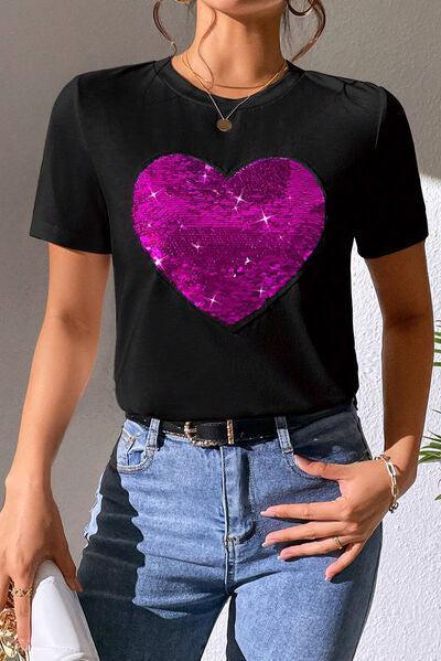 a woman wearing a black shirt with a pink heart on it