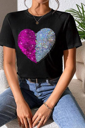 a woman sitting on a couch wearing a t - shirt with a heart on it