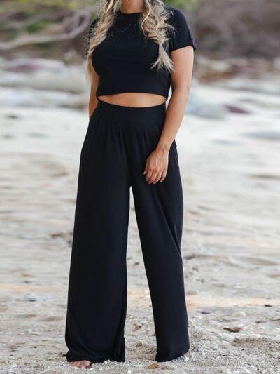 a woman wearing a black crop top and wide legged pants