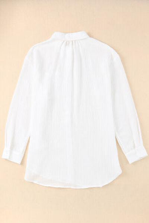 a women's white shirt is hanging on a wall