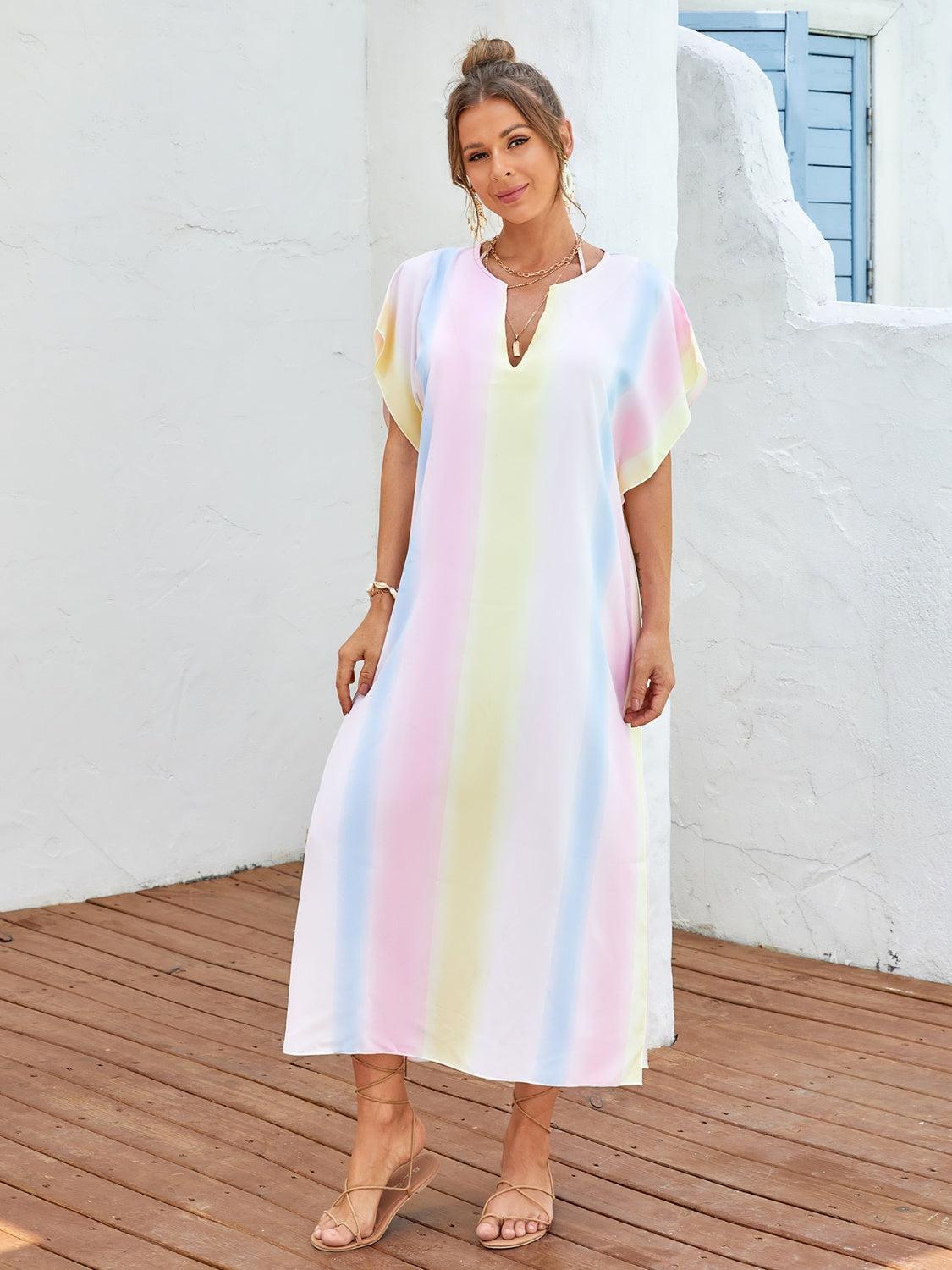 a woman standing on a deck wearing a rainbow colored dress
