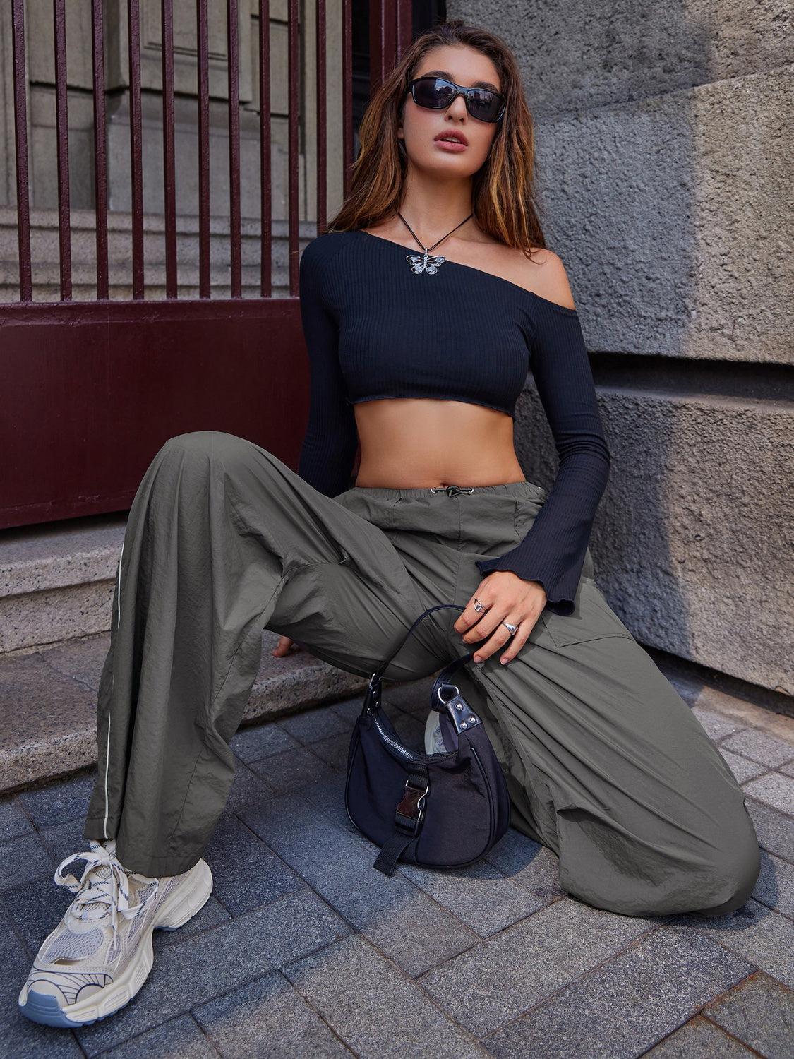 a woman sitting on the ground wearing a black top and khaki pants