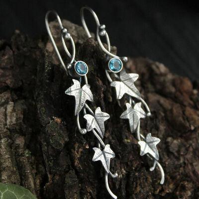 a pair of silver earrings with leaves and blue stones