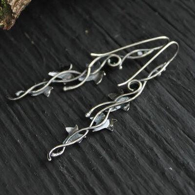 a pair of silver earrings sitting on top of a wooden table