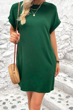 a woman wearing a green dress and a straw bag