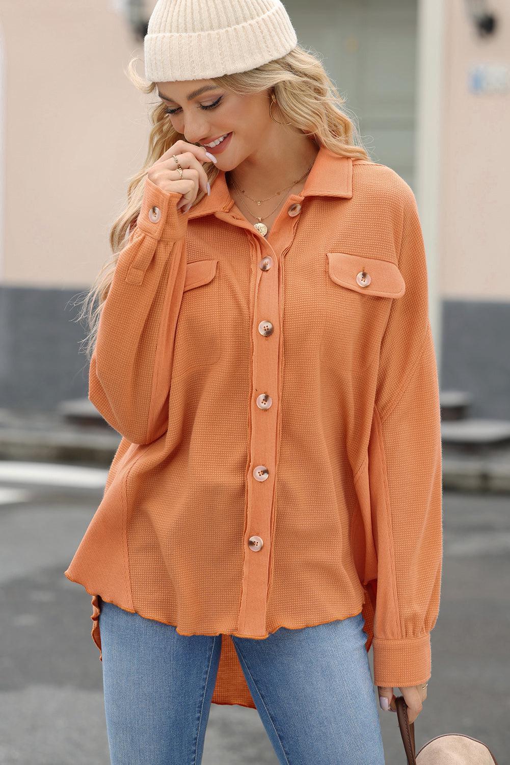 a woman in an orange shirt talking on a cell phone