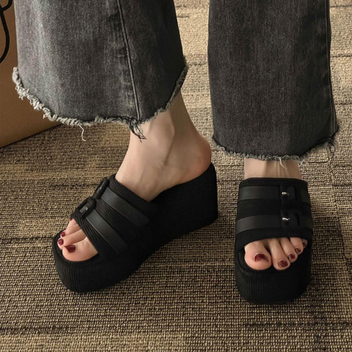 a person wearing black sandals and a pair of jeans