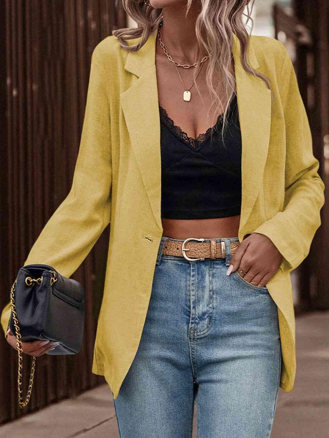 a woman wearing a yellow blazer and jeans