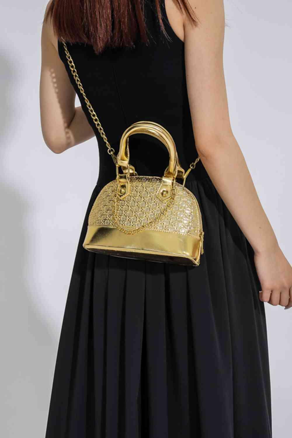 a woman in a black dress holding a gold purse