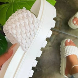 a woman's feet in white shoes and a plant