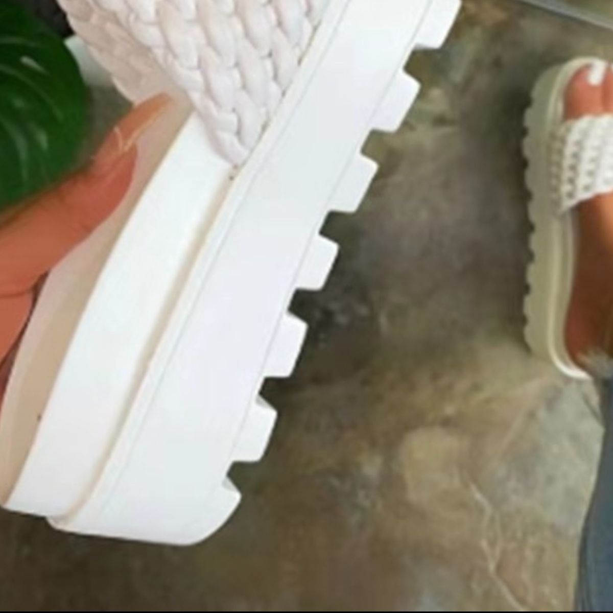 a pair of white shoes with a plant in the background