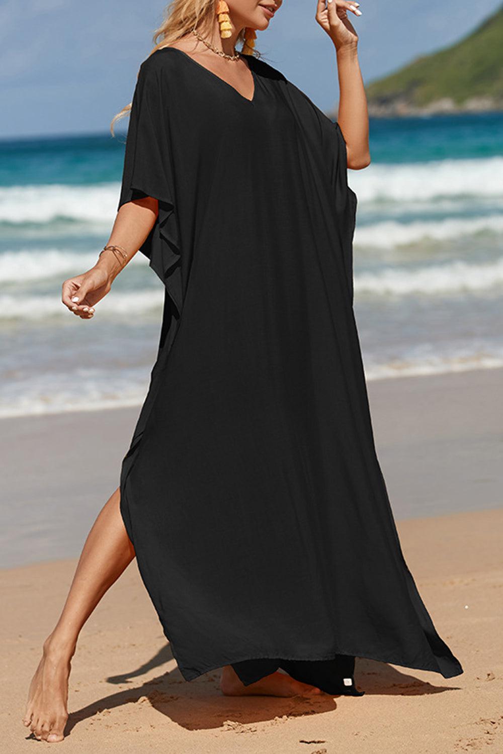 a woman in a black dress is walking on the beach