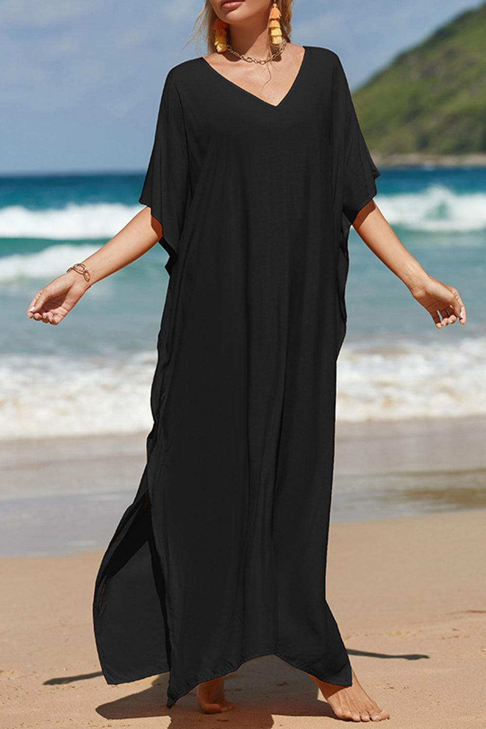 a woman standing on a beach wearing a black dress